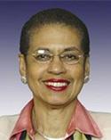 Eleanor Holmes Norton smiling in front of purple gradient background wearing cream jacket and pink collared shirt