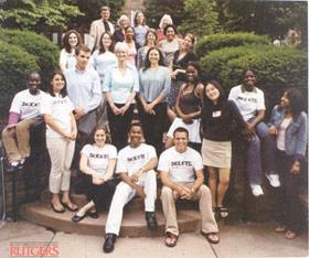 Susie Wilson posing on outdoor steps with teens sitting and standing around her.