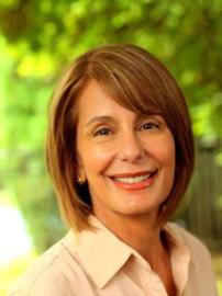 Barbara Buono smiles in beige shirt with greenery in background